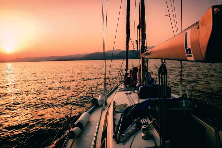 2 people sailing on a boat during sunset